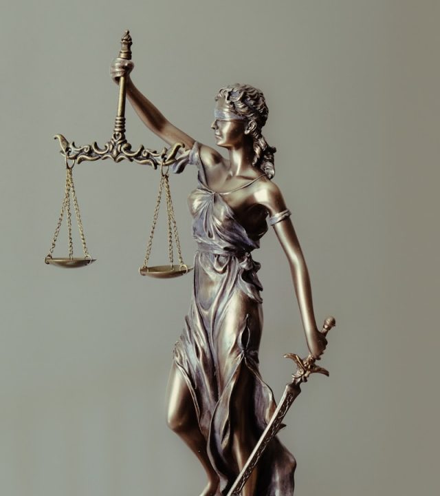 Photo by Tingey Injury Law Firm woman in gold dress holding sword figurine